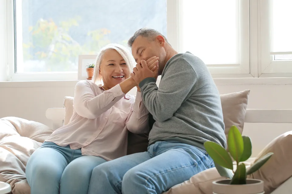 A retired couple laughing together on the sofa at home in San Antonio