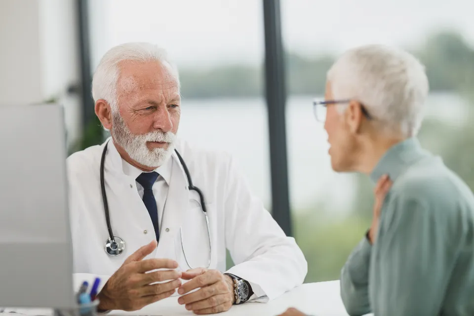 An older woman talking with her doctor at a clinic desk