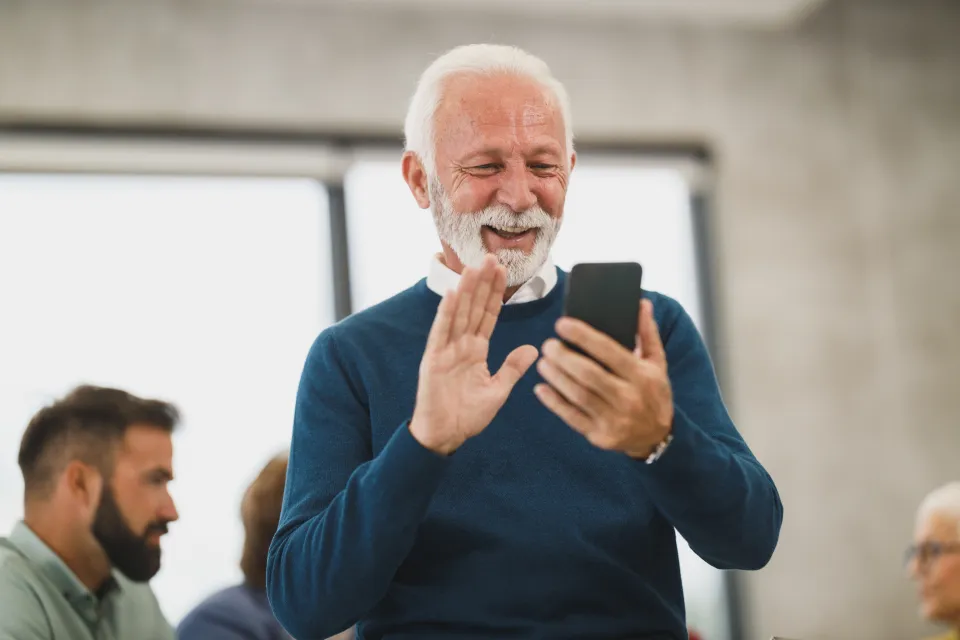 A smiling older man on a video call from his phone